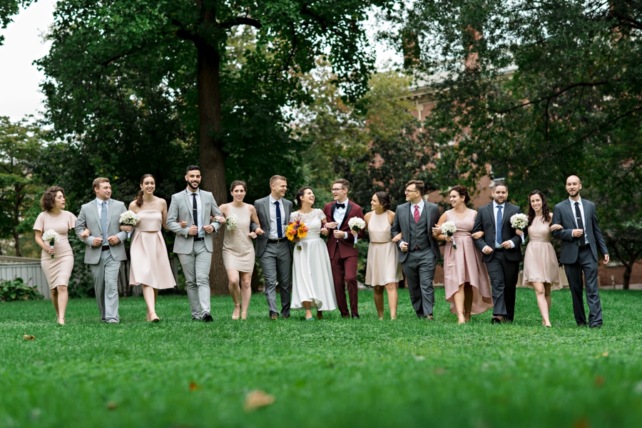 A wedding party walk arm in arm across a park in Philadelphia.